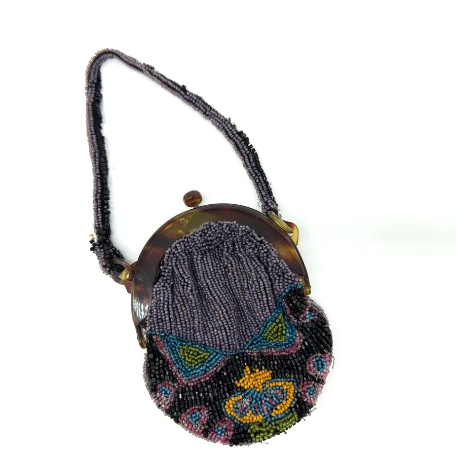 1920s Art Deco beaded evening purse with tortoiseshell frame, iridescent glass beads in geometric patterns, hanging from blac