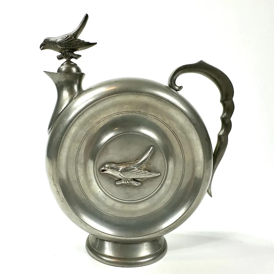 1934 Swedish Art Deco pewter flask with raven finial and relief design, front three-quarter view showing intricate metalwork