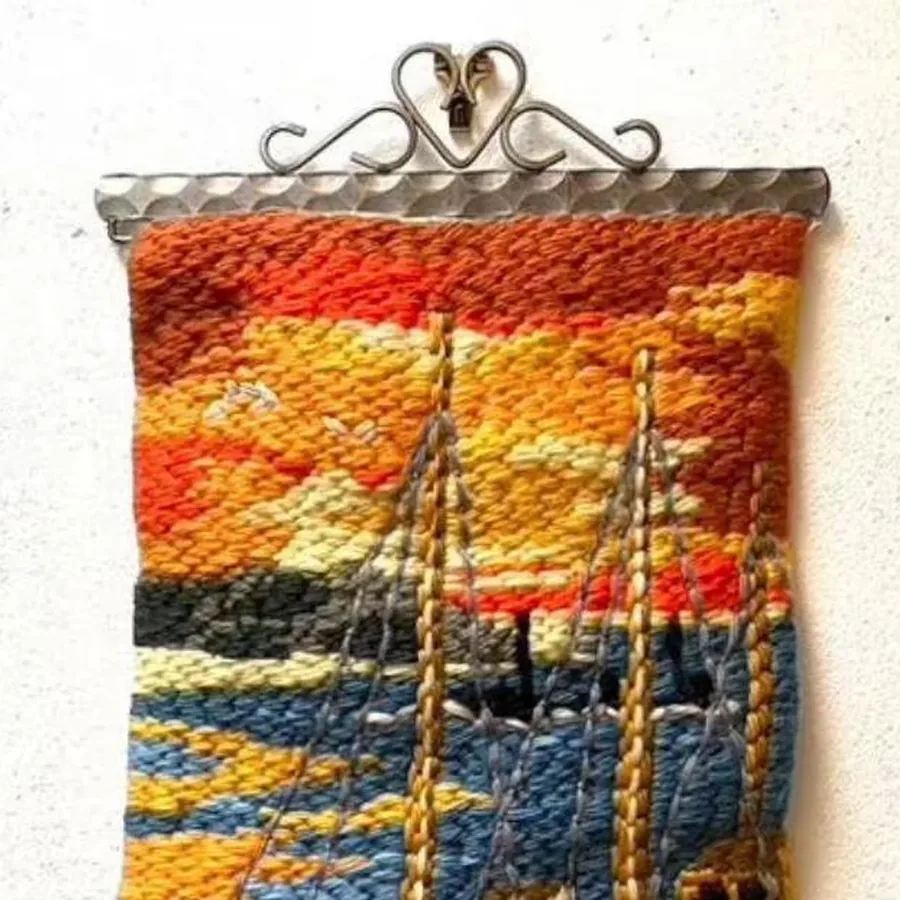 Angled view of vintage tapestry showing ornate metal mounting bracket with heart detail, full nautical composition