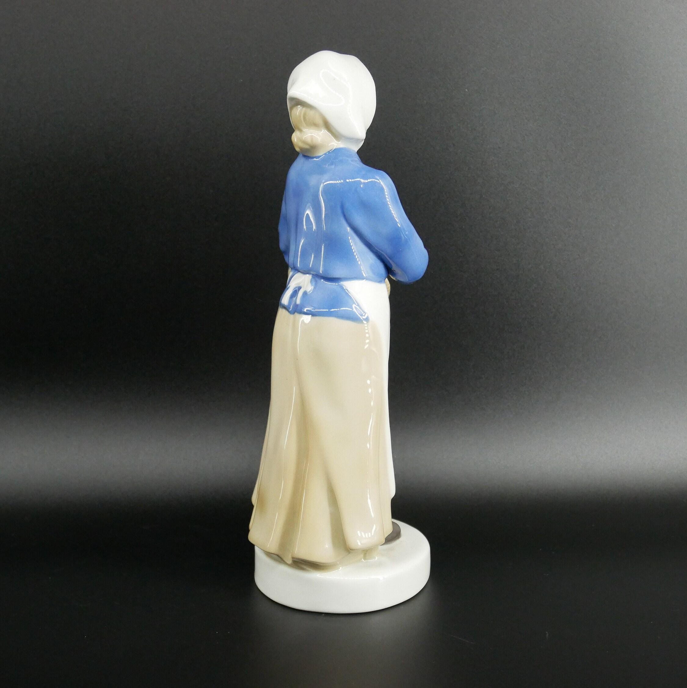 Back view of porcelain fisherwoman figure highlighting form and hand-painted jacket details from rear