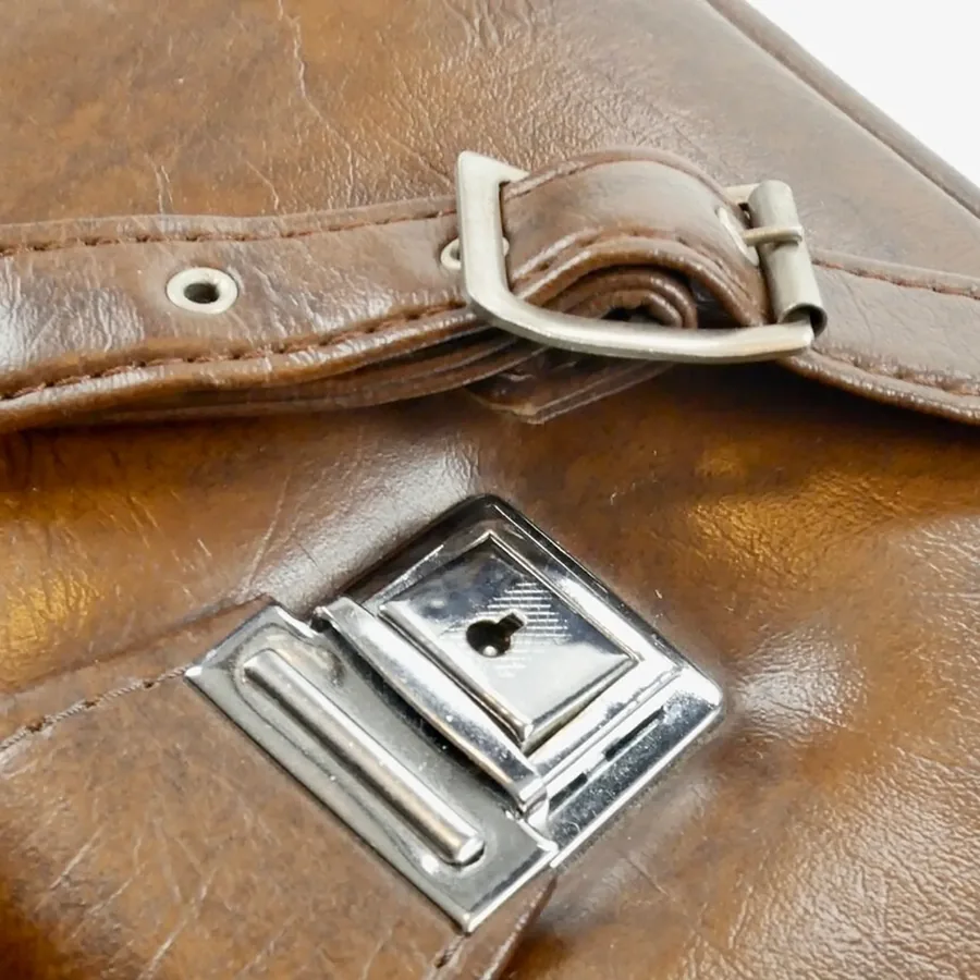 Close-up of brass turnkey clasp and stitched leather flap showing working mechanical closure hardware