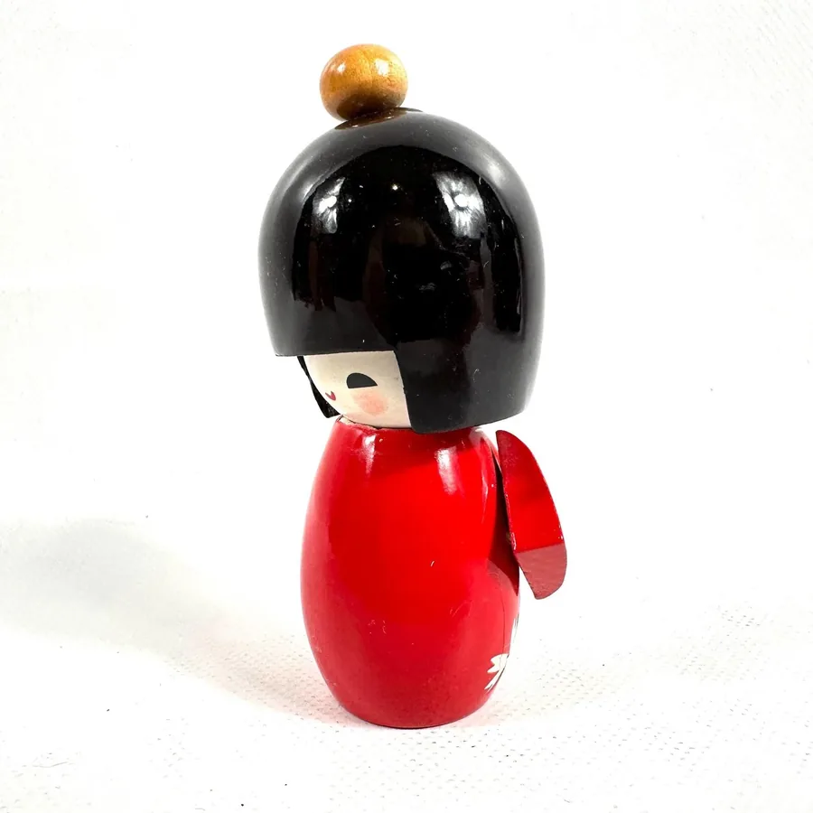 Close-up of kokeshi doll's face showing hand-painted features and glossy lacquered black hair detail