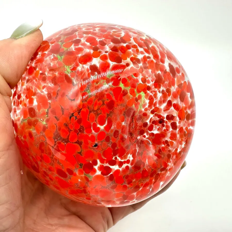 Close-up of red glass tomato showing luminous speckles and smooth polished glass surface texture