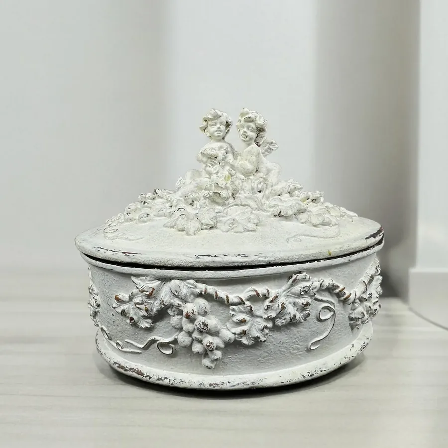 Complete Rococo cherub jewelry box with twin angel finials and floral relief carving on neutral background