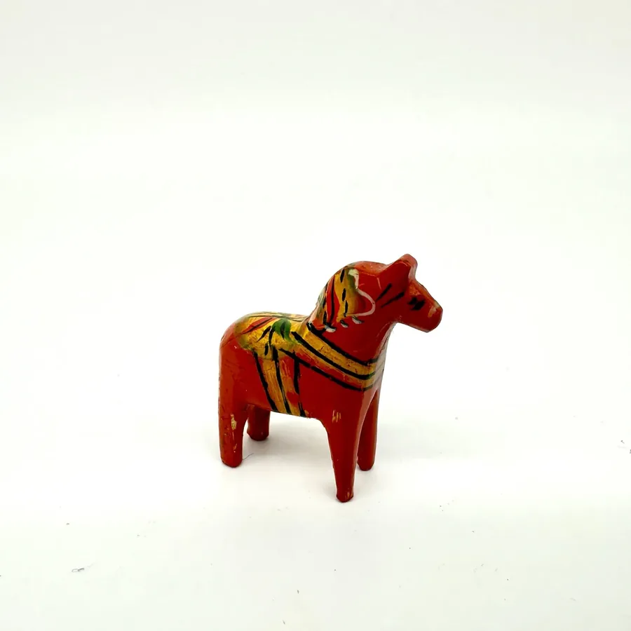 Front-facing Dala horse miniature, showcasing painted facial features and carved head details, traditional Swedish folk art c