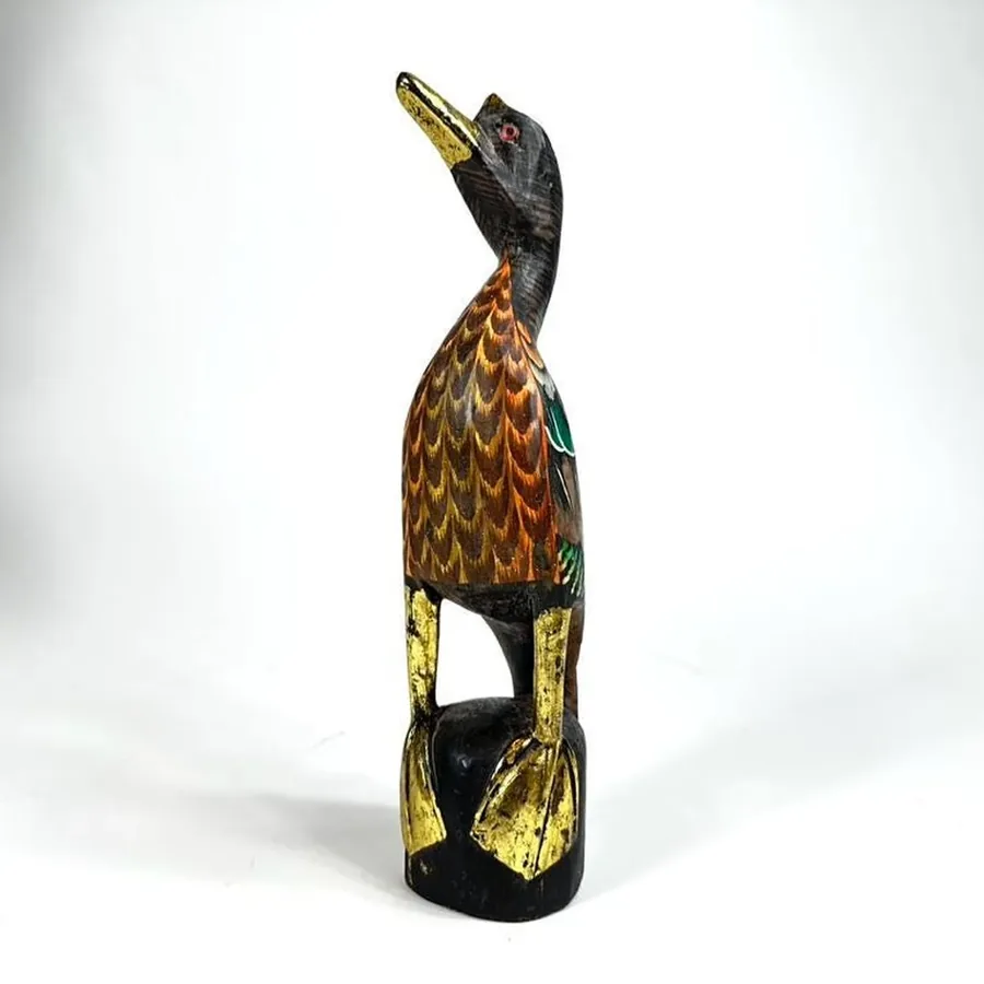 Front-facing view of wooden duck showing expressive facial features, hand-painted eyes, and gold accent highlights