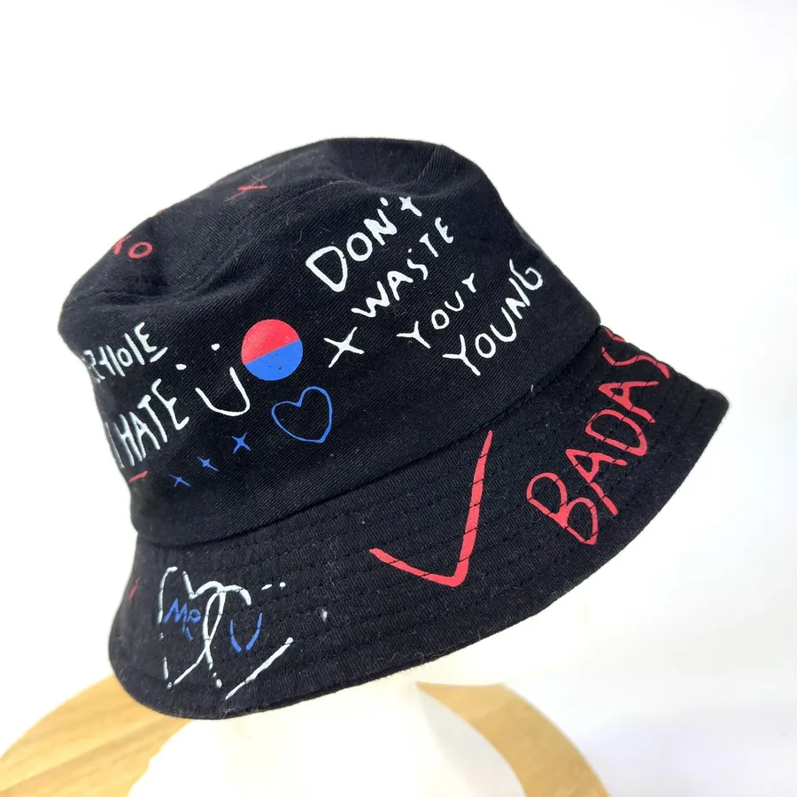 Full front view of graffiti bucket hat displaying 'Don't Waste Your Young', red 'BADASS', and complete punk slogan artwork ac
