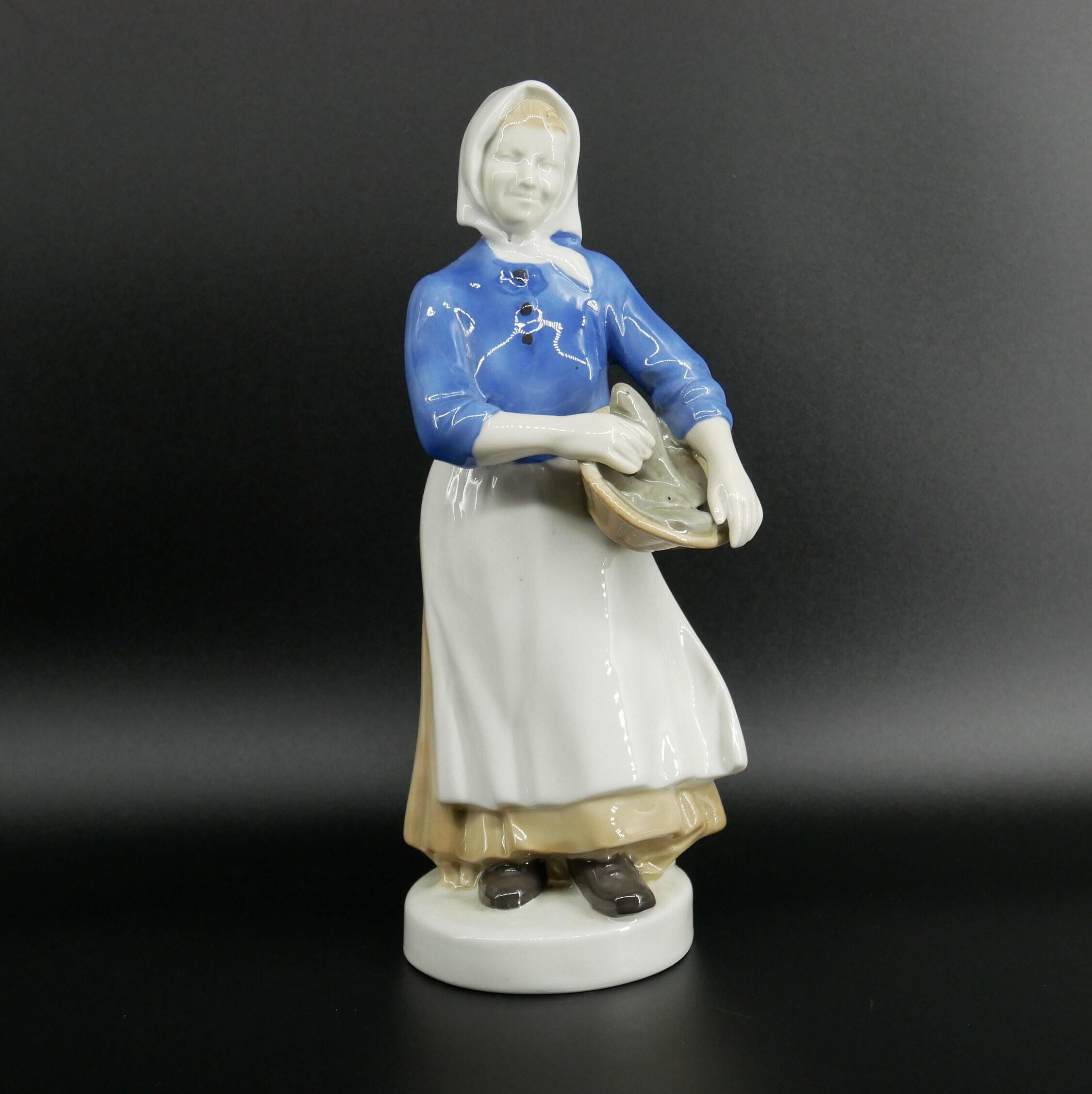 Full frontal view of Carl Scheidig fisherwoman in blue painted jacket and cream skirt holding basket