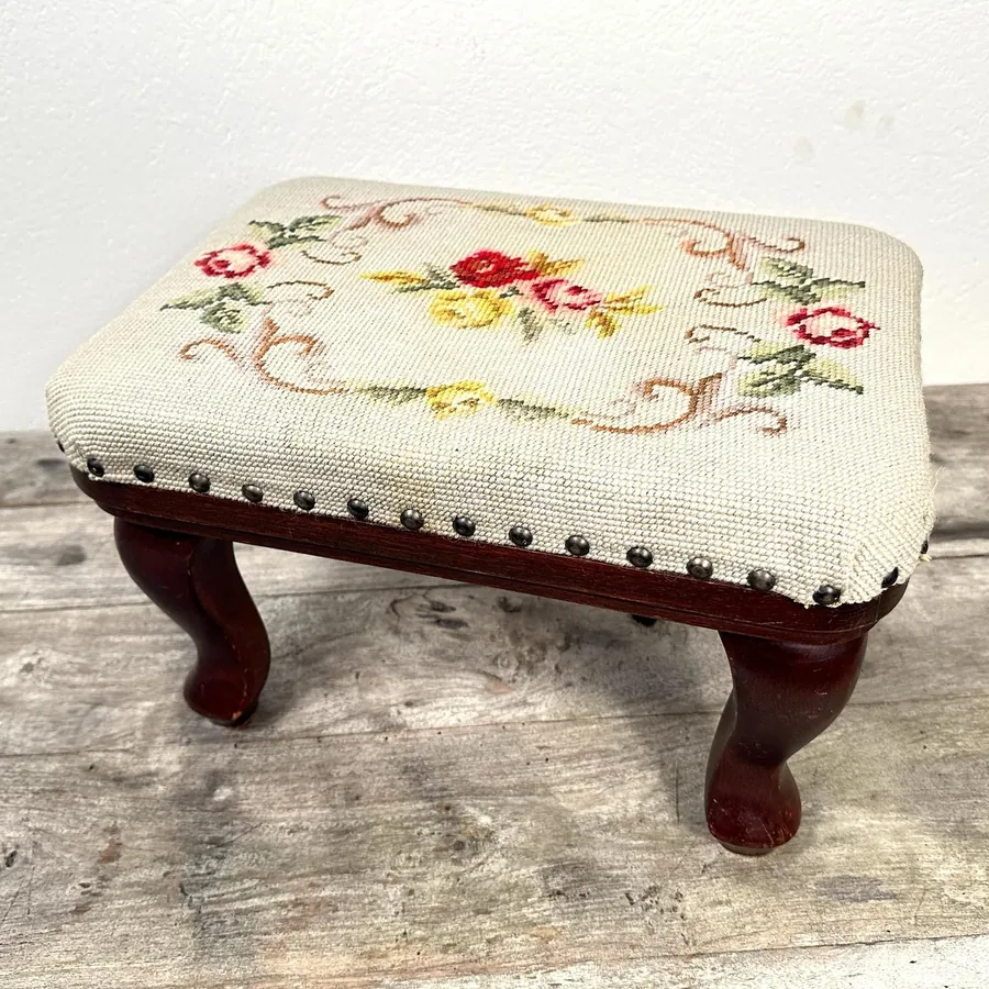 Full ottoman showing complete needlepoint design layout with centered floral composition on vintage upholstery