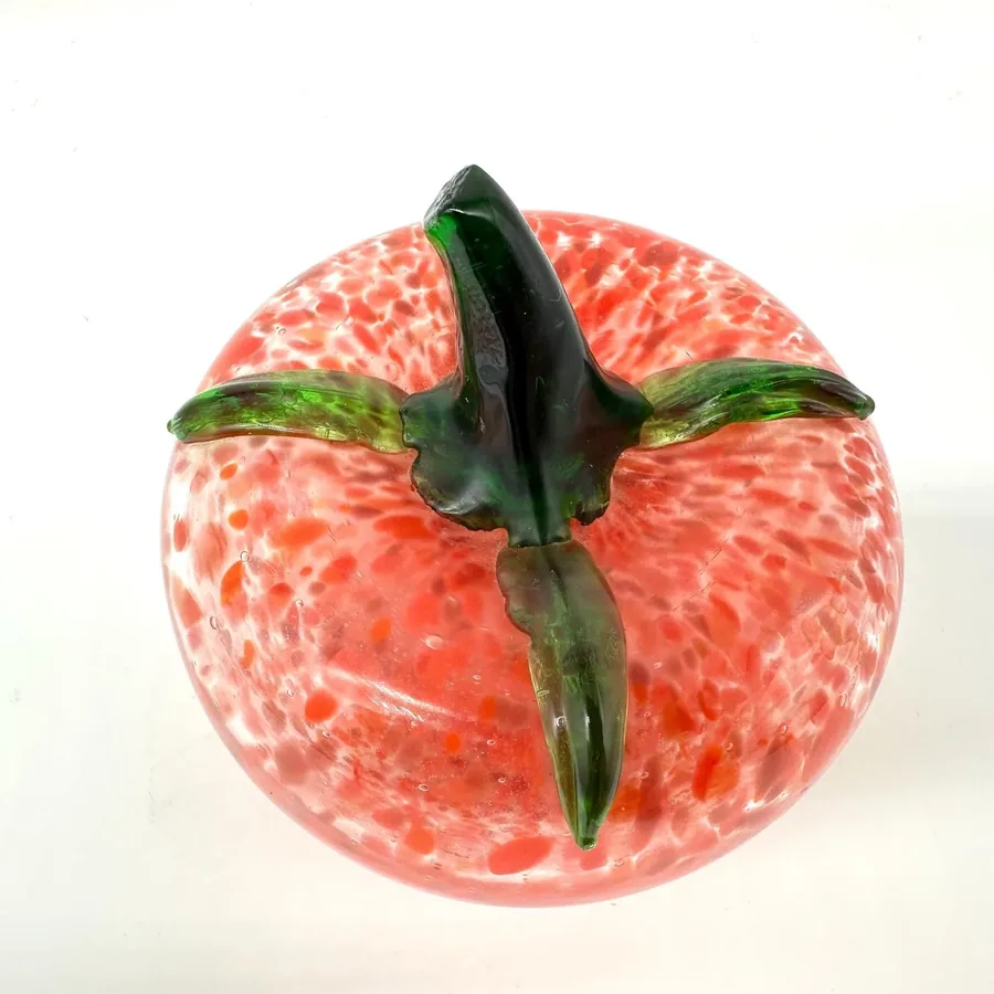 Glass tomato from above showing stem detail and radiant speckled red surface in clear view