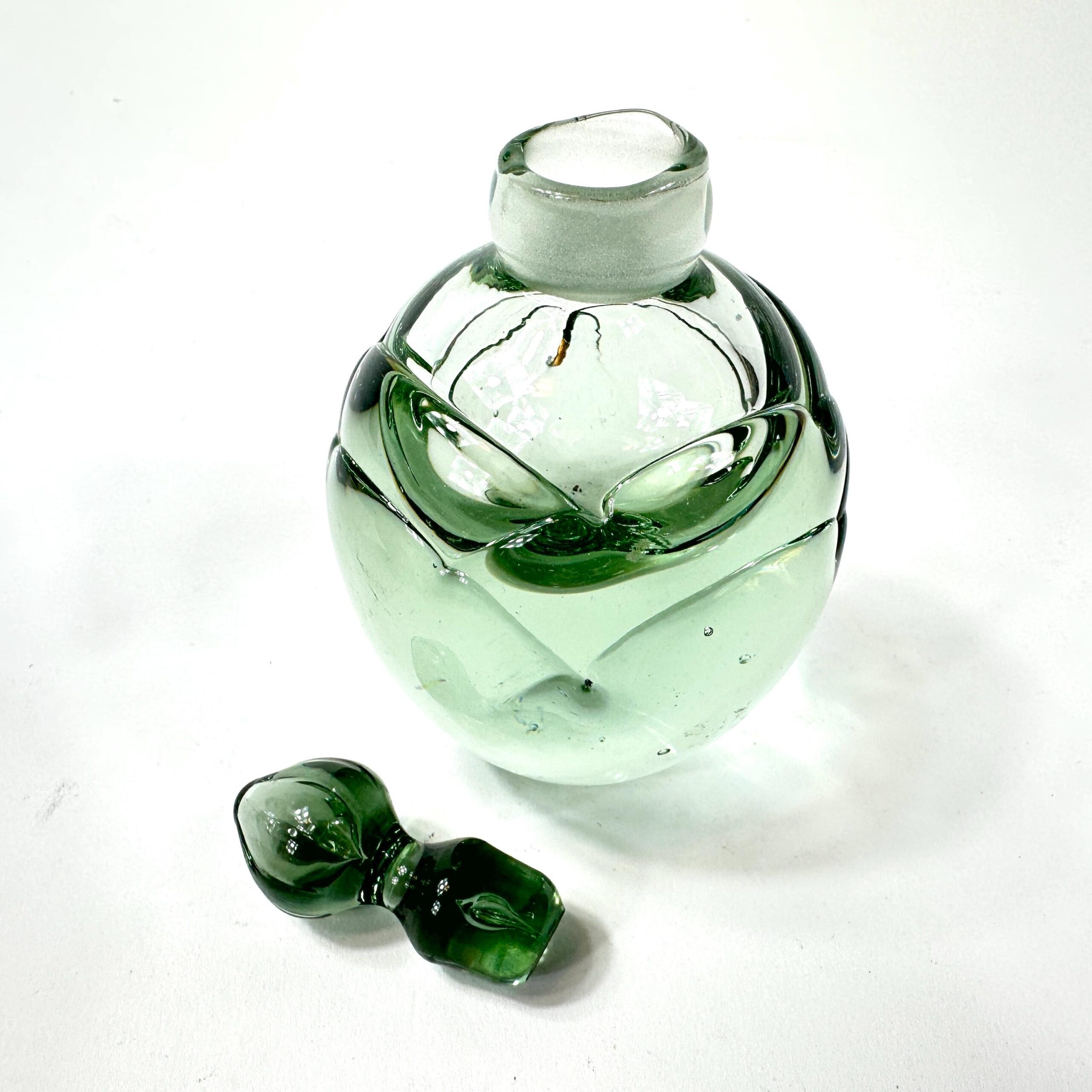 Green glass perfume bottle base and bottom detail showing signed artist mark