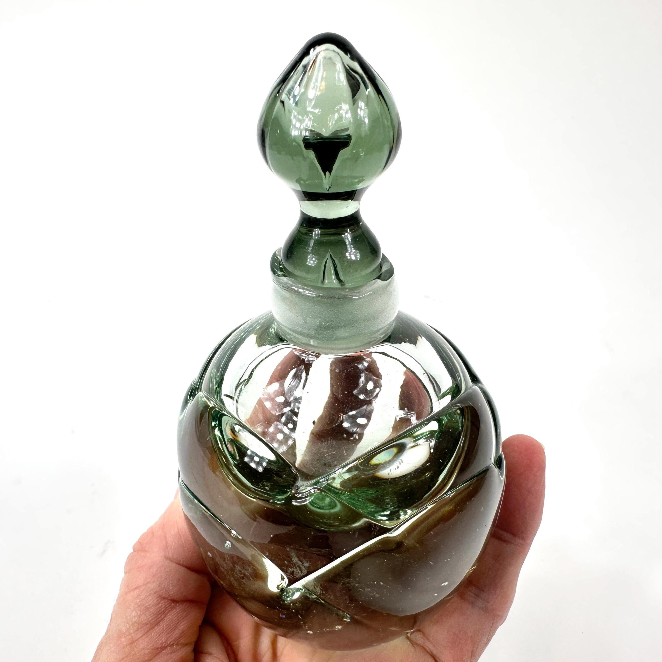 Green glass perfume bottle photographed against light showing internal glass clarity
