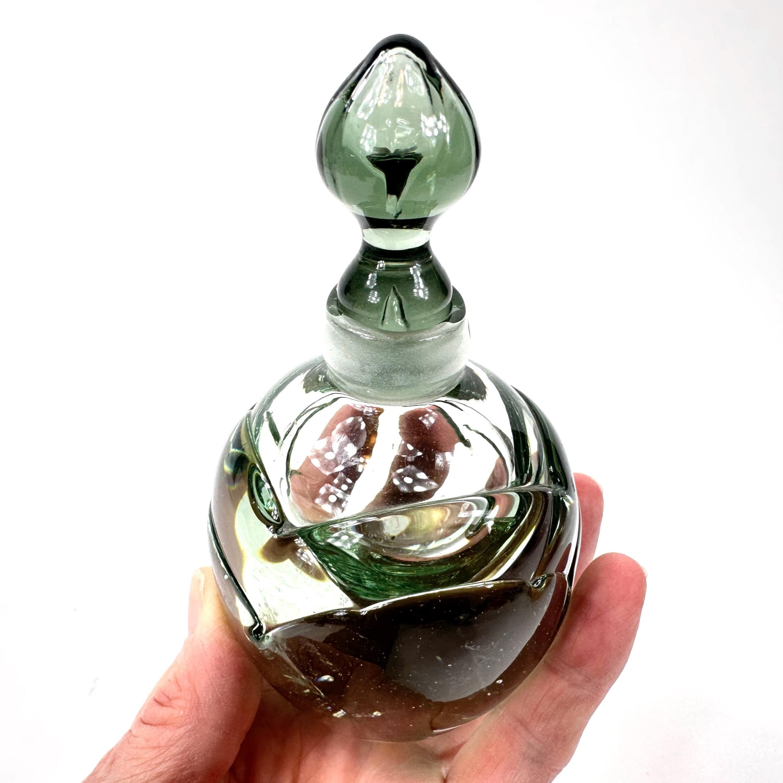 Green perfume bottle styled on vanity displaying retro 1990s studio glass artistry