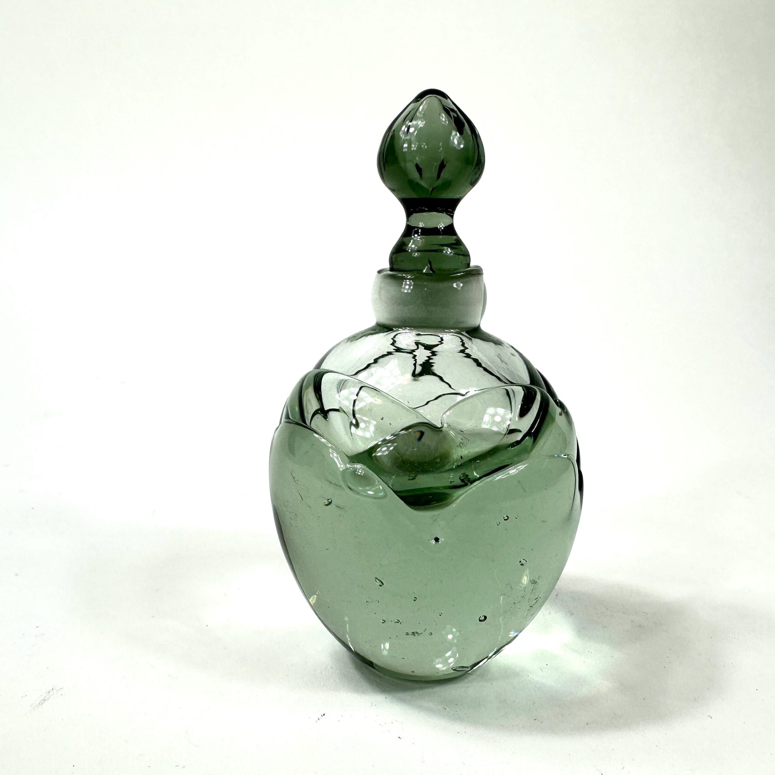 Green studio glass bottle showing curved contours and glass depth, angled perspective view
