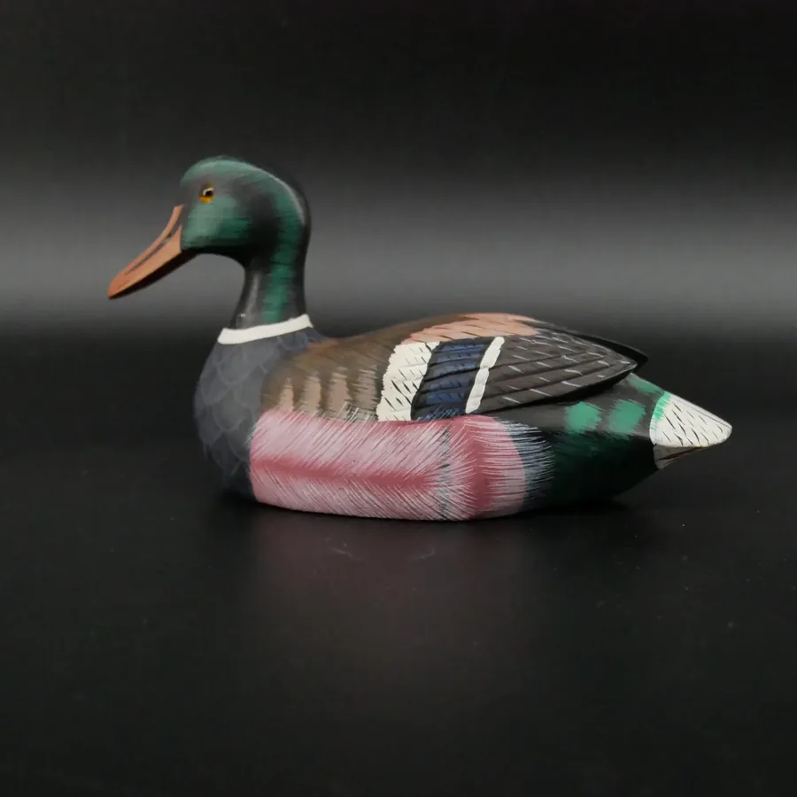 Hand-carved wooden decoy duck in natural lighting, rustic mallard showing complete weathered patina