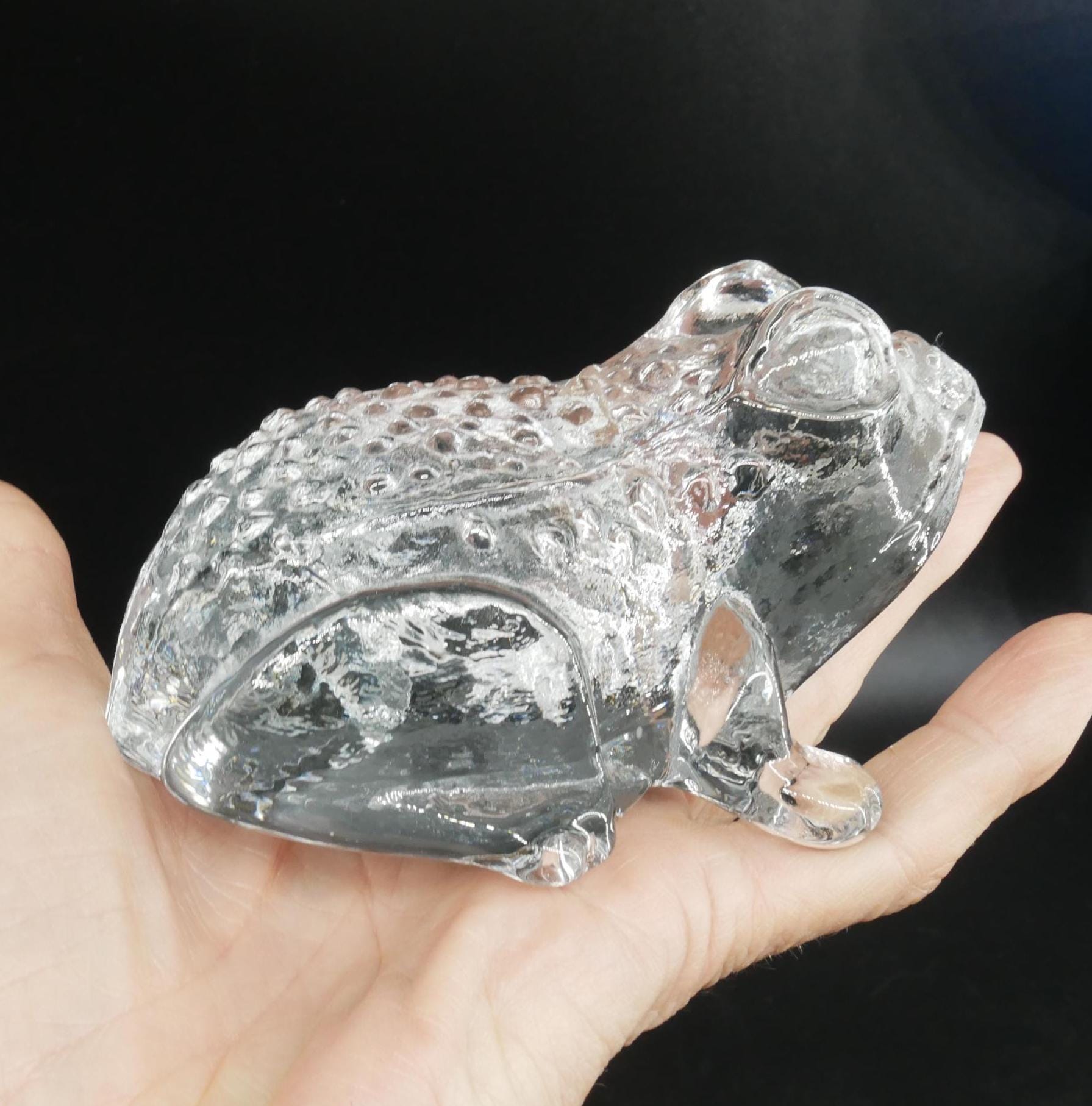 Kosta Boda glass frog held in hand, showing scale and translucent crystal quality, intimate scale