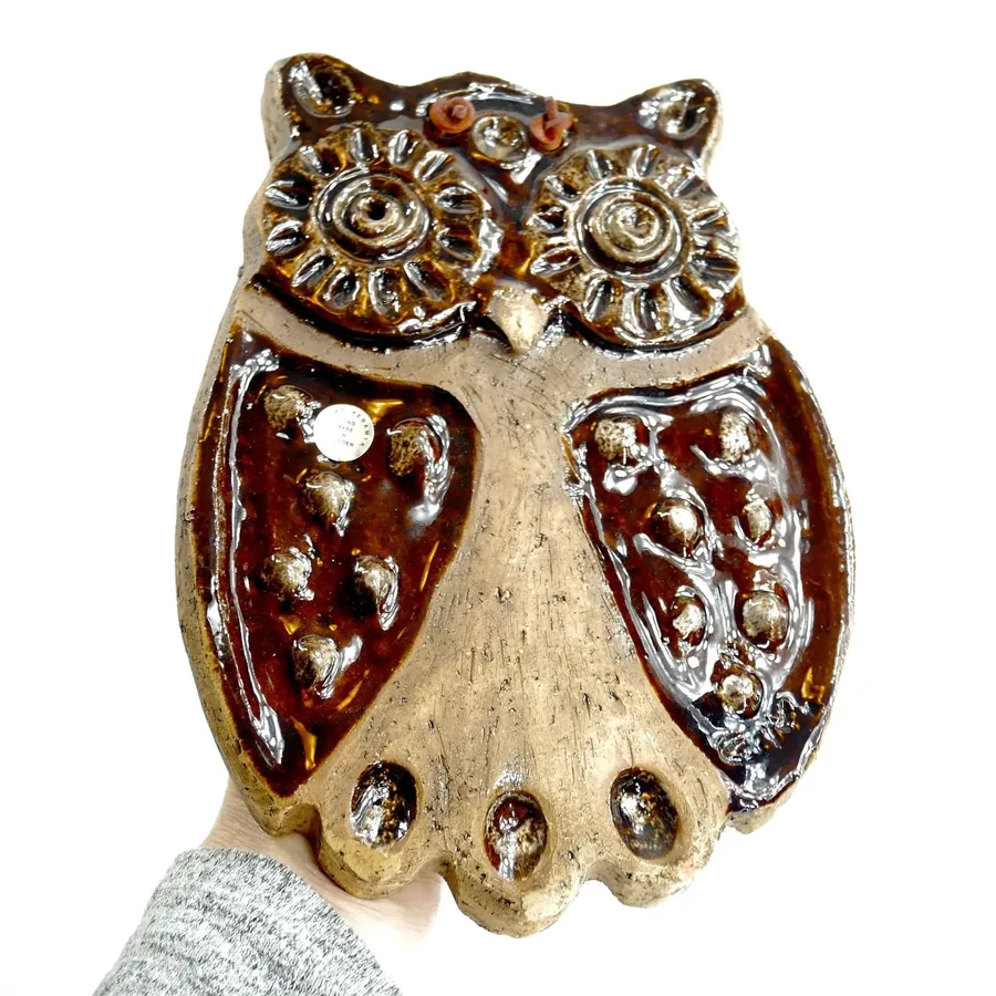 Laholm owl plaque hand-held detail shot showing molded face, textured wings, warm brown glaze, mounting holes visible