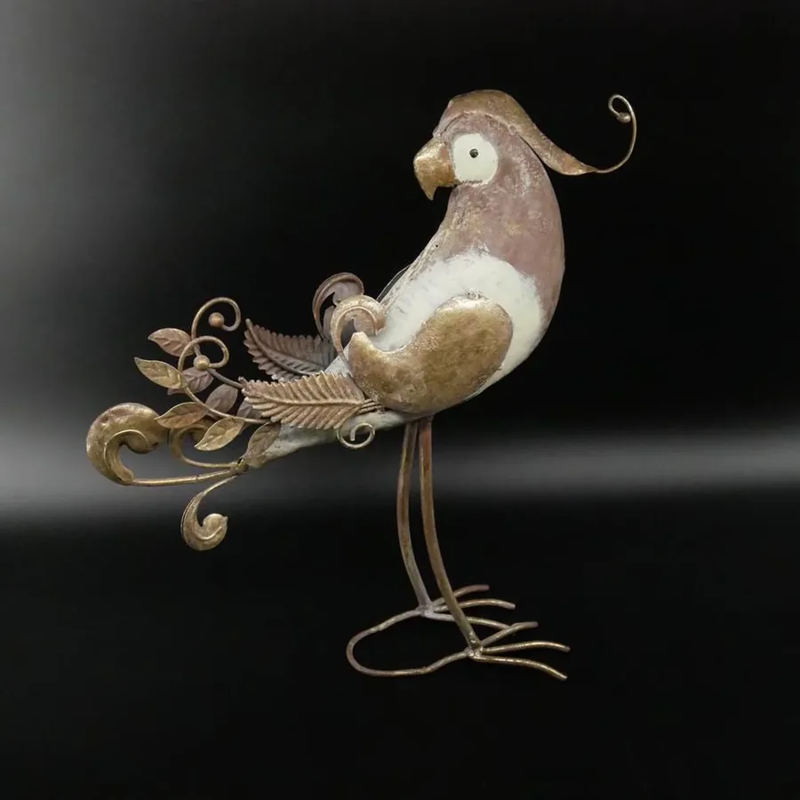 Metal parrot from side showing curved beak, silver-gold coloring, and intricately scrolled tail design