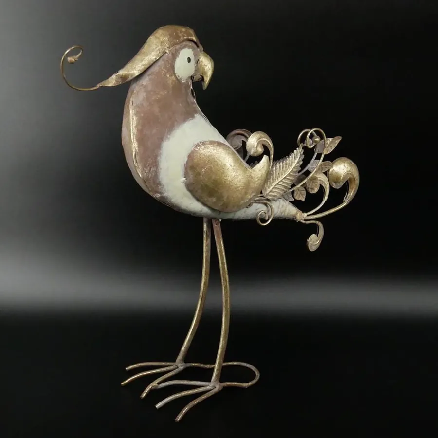 Metal parrot sculpture side view displaying white chest, golden belly, and scrollwork tail accents against dark backdrop