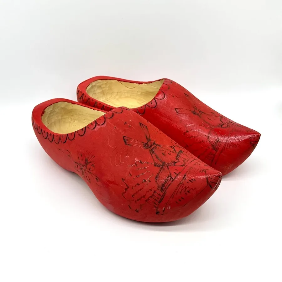 Pair of vintage Dutch wooden clogs in bright red with hand-painted windmill and folk art scenes, cream linen interiors, angle