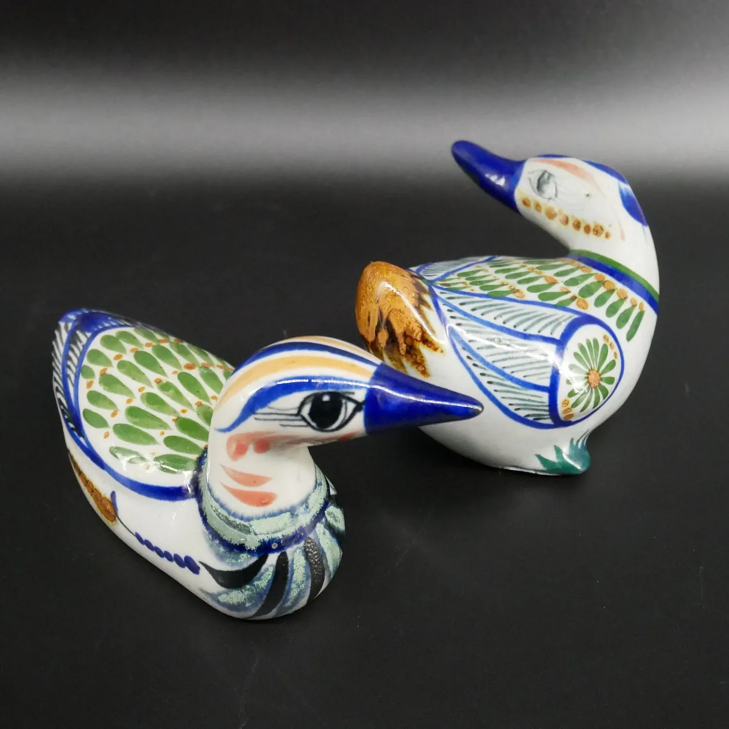 Pair of vintage Tonala pottery ducks with hand-painted blue, green, and cream glazes, featuring artist signatures and traditi