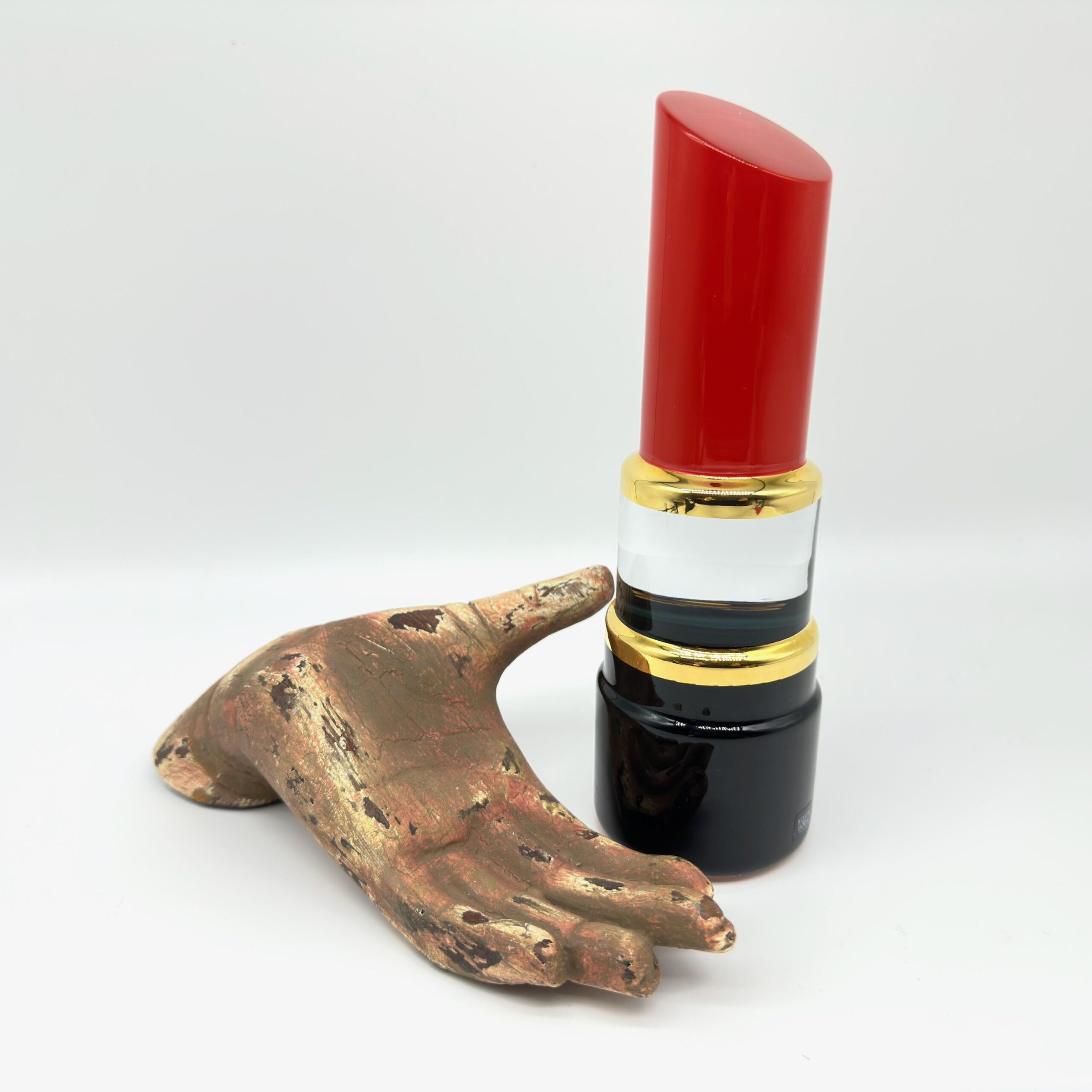 Red Hot lipstick with bronze hand sculpture, display styling showing artistic context and scale