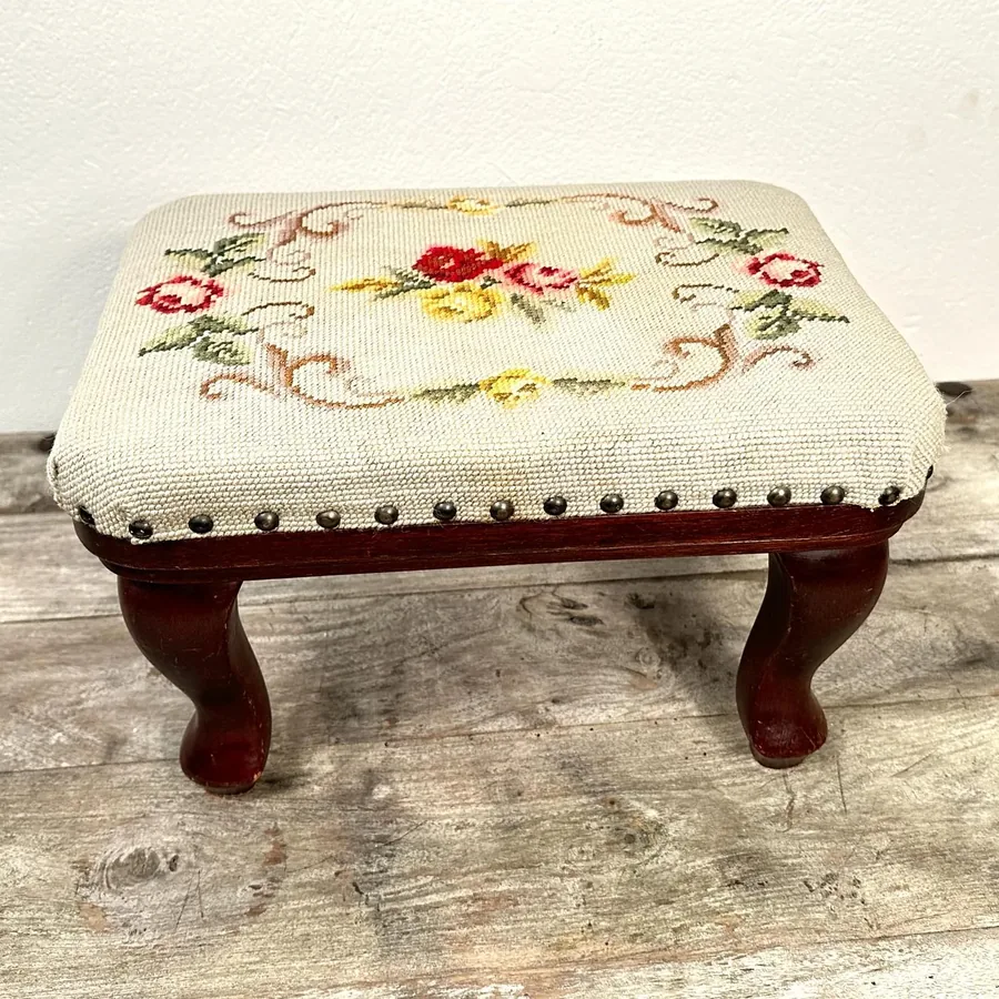 Resting position view of vintage Swedish needlepoint stool on flat surface showing proportions, wood legs, and embroidered to