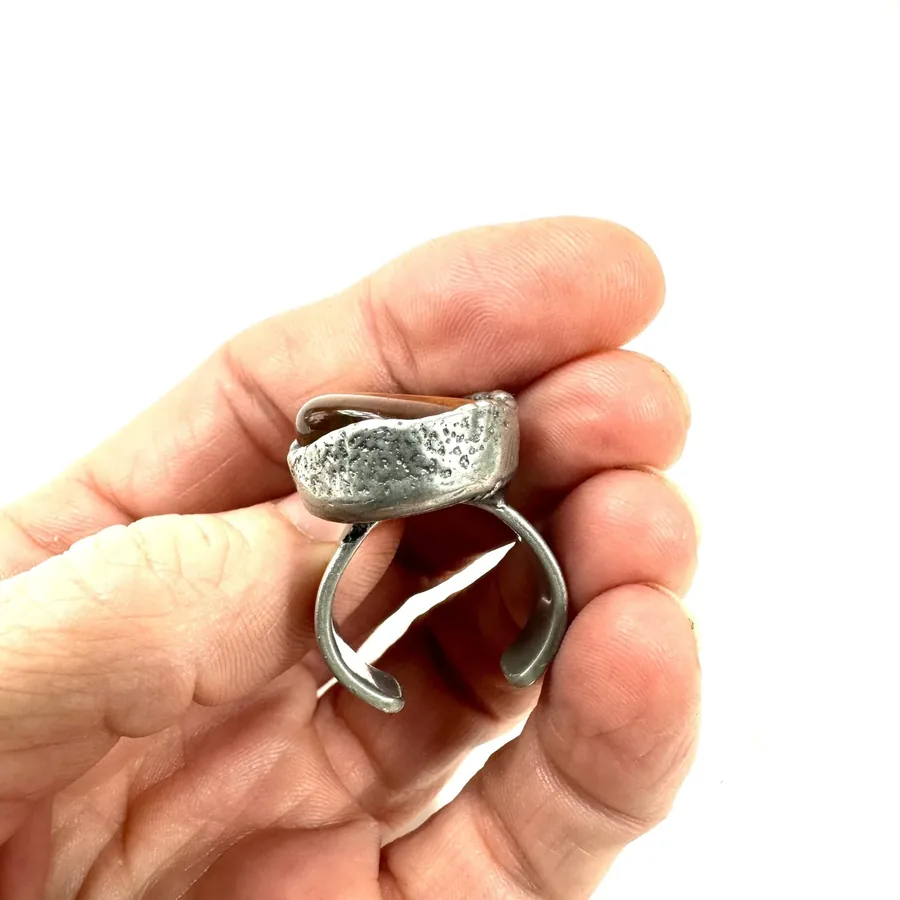 Ring angle showing three-dimensional depth, silver setting surrounding Tiger's Eye with visible brutalist edges