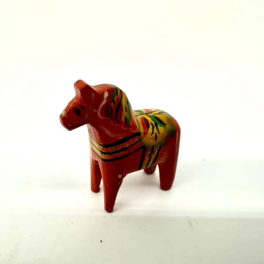 Scale reference view of miniature Dala horse with hand positioning, showing compact size and portable vintage Swedish folk ar