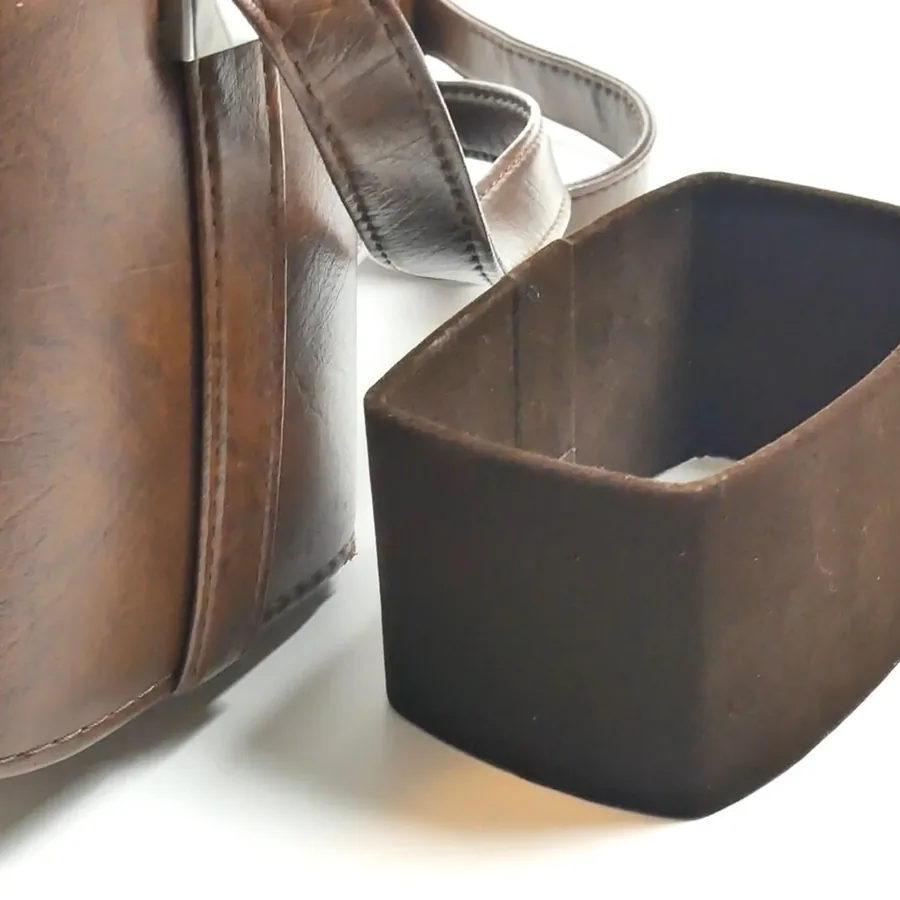 Side-by-side detail showing worn brown leather exterior patina next to dark interior fabric compartment