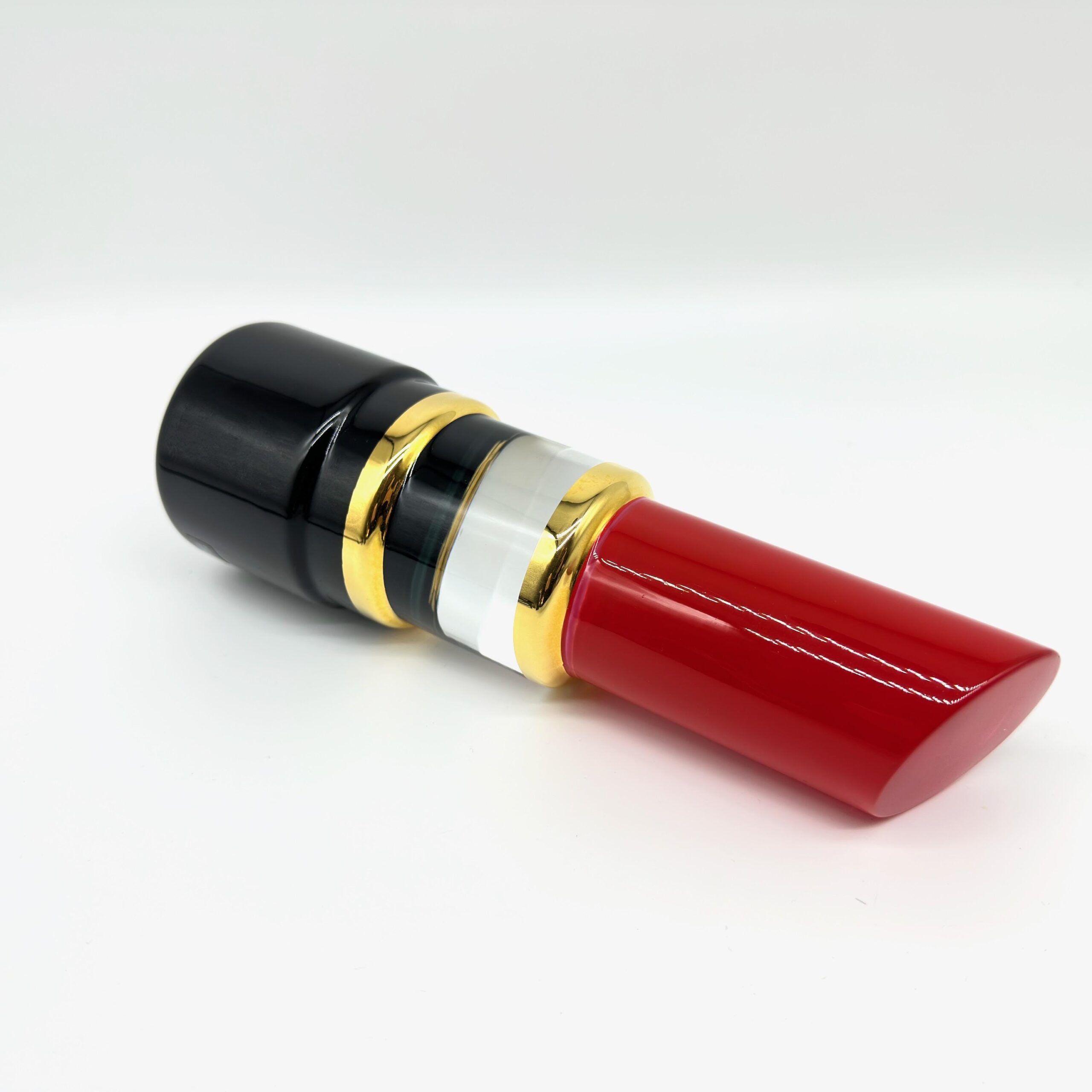 Side profile of red lipstick sculpture showing the dramatic taper and functional form against neutral ground