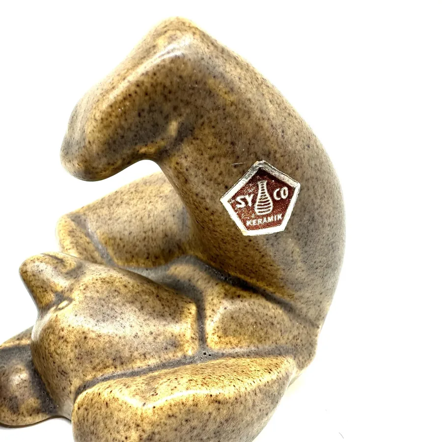 Single ceramic bear figurine close-up, showing maker's mark pentagon detail and smooth sculptural contours of head and should