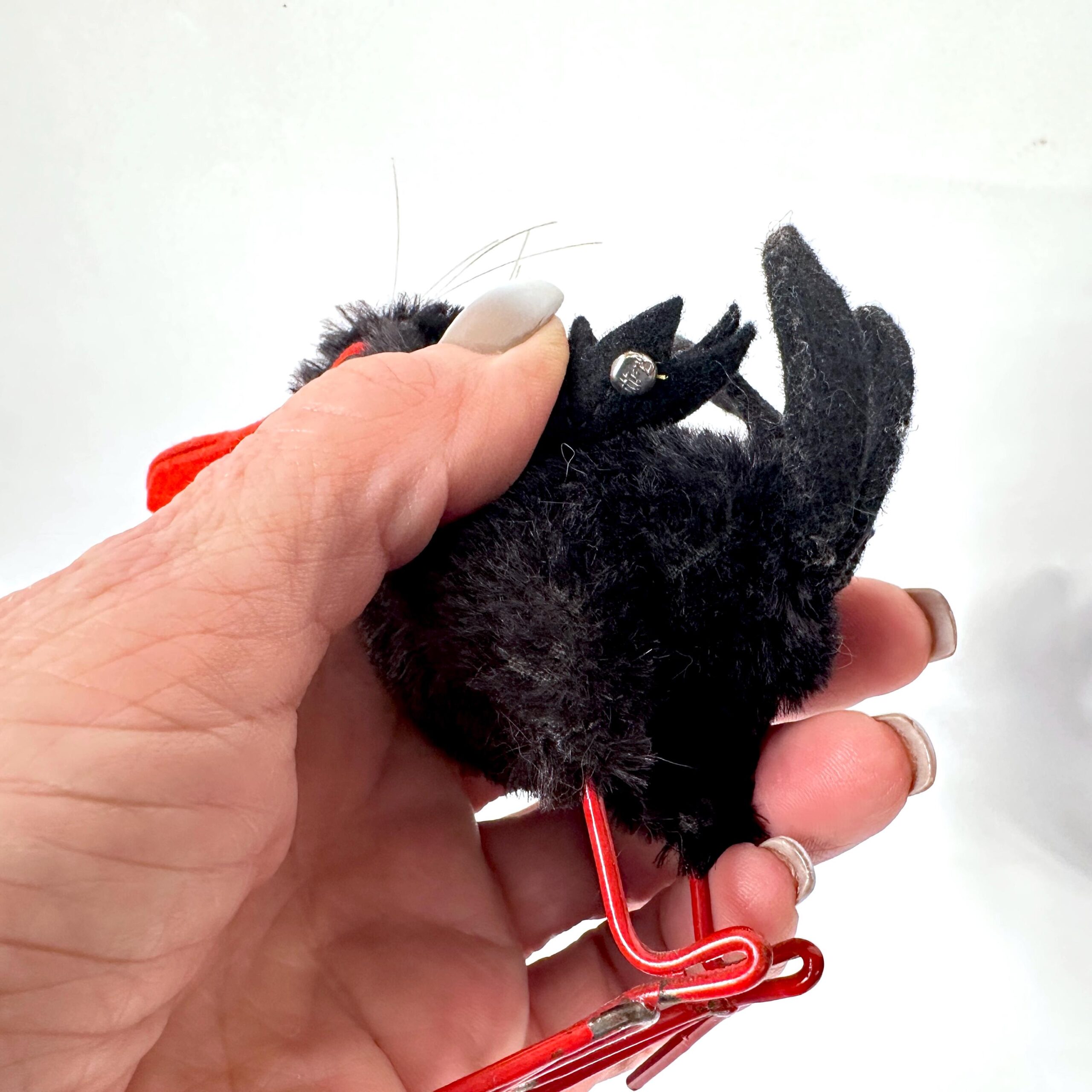 Small Steiff Hucky Bird positioned sideways showing jointed head turned profile, mohair body texture, orange beak angle, and