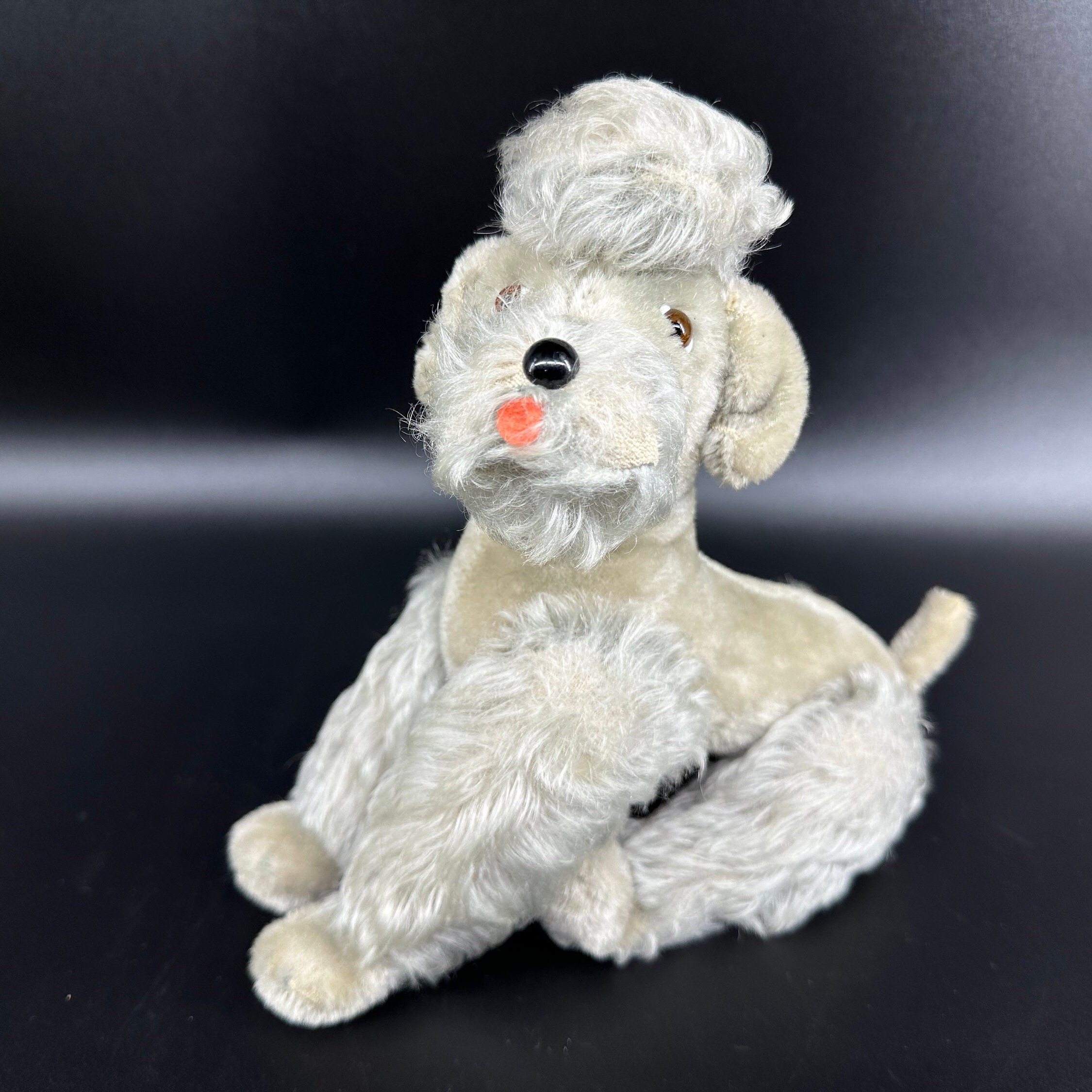 Steiff poodle side-lying view showing profile of face and extended body length in relaxed position