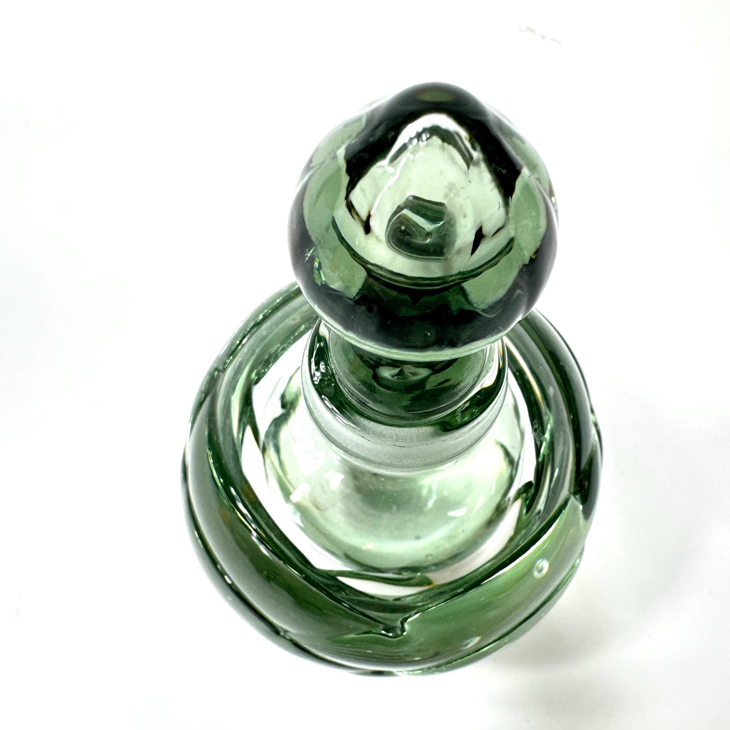 Studio glass bottle illuminated to highlight transparent green hue and glass thickness