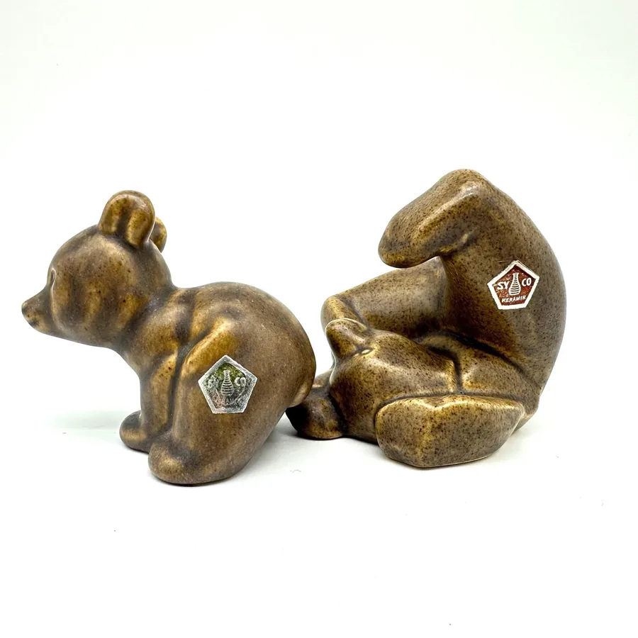 Three vintage ceramic bears arranged in tumbling formation, showing varied poses with visible maker's marks and patina