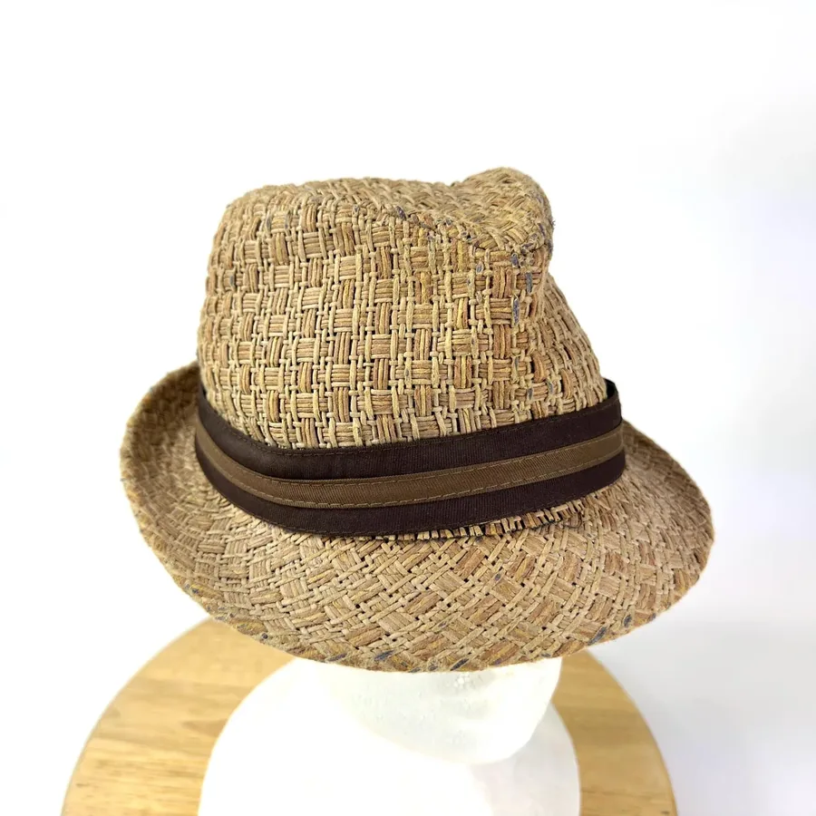 Tilted view of natural woven fedora displaying crown texture, grosgrain ribbon detail, and bucket-style silhouette