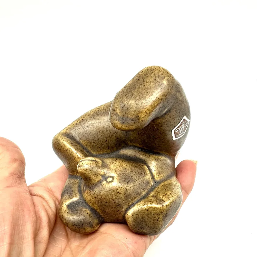 Tumbling bear figurine held in hand, highlighting compact scale and maker's mark pentagon stamp on ceramic surface