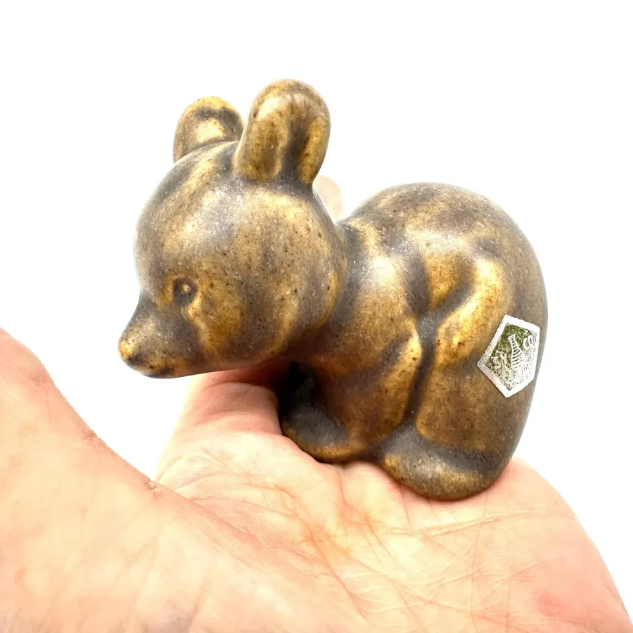 Two ceramic bears nested together in hand, showing playful interaction, maker's marks, and warm glaze coloration throughout