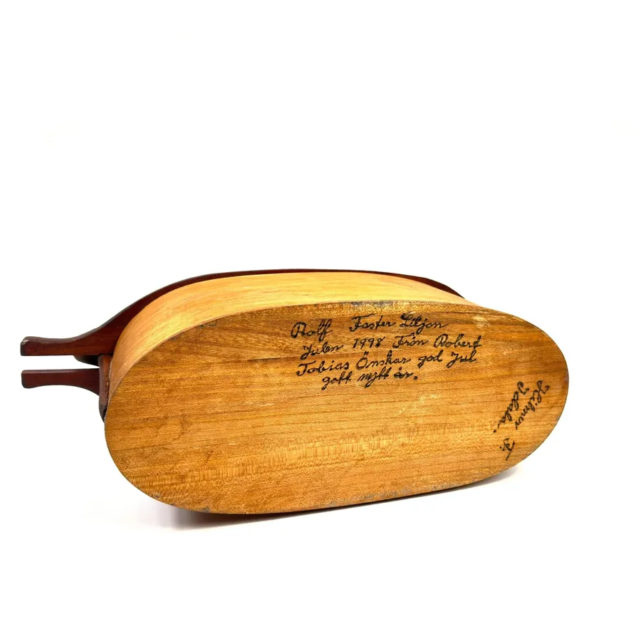 Underside of bentwood box lid showing wood grain, craftsman's signature, and aged patina details