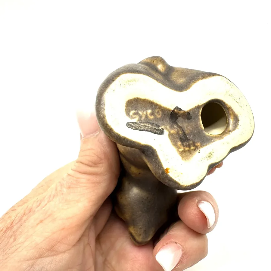 Underside of ceramic bear showing hollow interior cavity and impressed factory mark indicating authentic Syco pottery constru