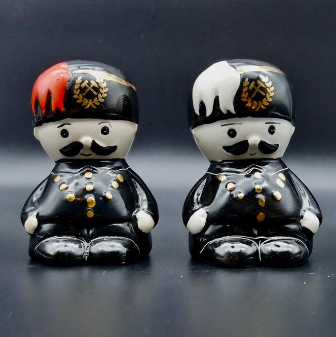 Charming retro military cruet set with hand-painted ceramic details and nostalgic charm perfect for vintage collectors. Vintage ceramic toy soldier salt and pepper shakers with black uniforms, gold buttons, and hand-painted red and white feather