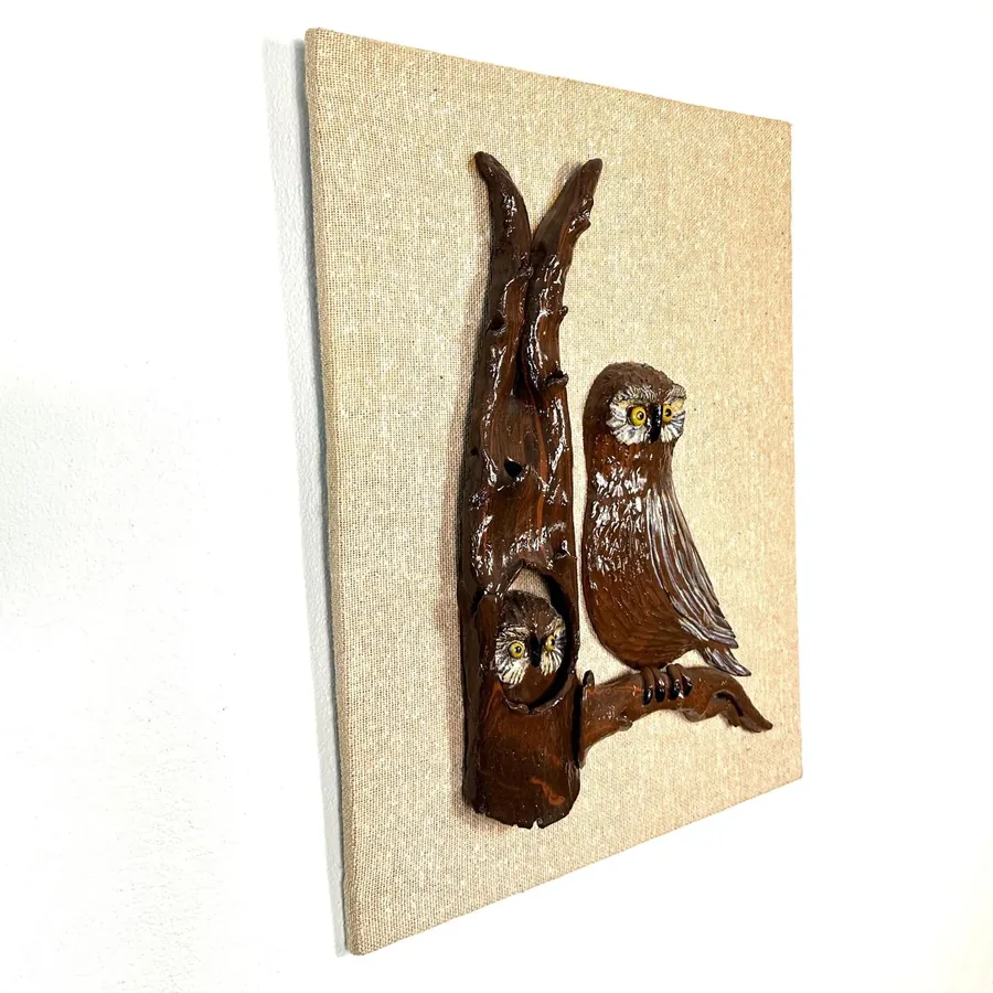 Vintage handmade ceramic owls on natural linen wall hanging, angled three-quarter view showing carved wood perch and textured
