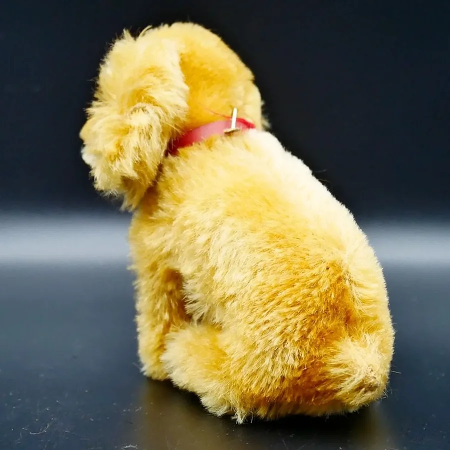 Vintage Steiff spaniel rear view displaying rounded back, pink ribbon collar, and tail positioning in sitting stance