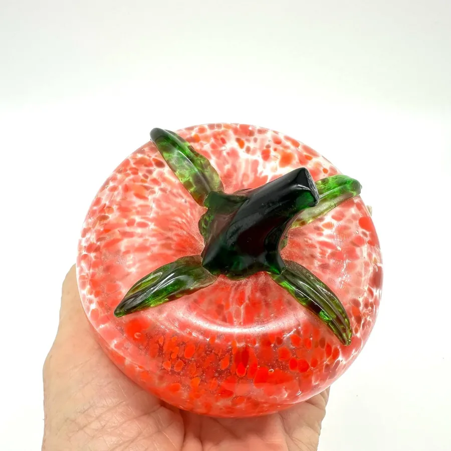 Vintage tomato sculpture held in palm showing complete form with green stem and full speckle coverage