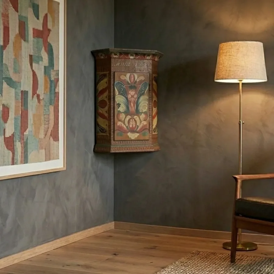 1960 Swedish Kurbits corner cupboard with hand-painted rosemaling folk art in warm wood tones, displayed in modern interior s