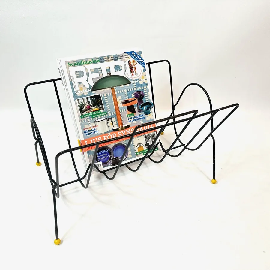 1960s atomic magazine rack final angle showing complete silhouette with loaded publications and distinctive yellow ball feet