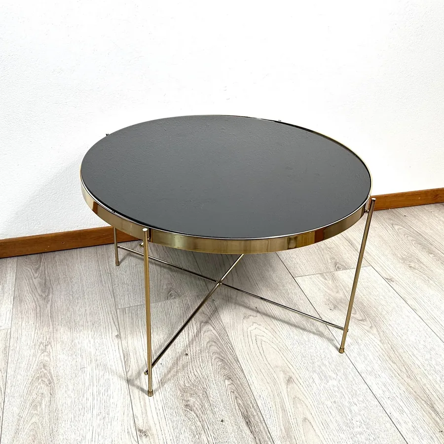 1970s Scandinavian brass side table with polished frame and round black glass top, angled view