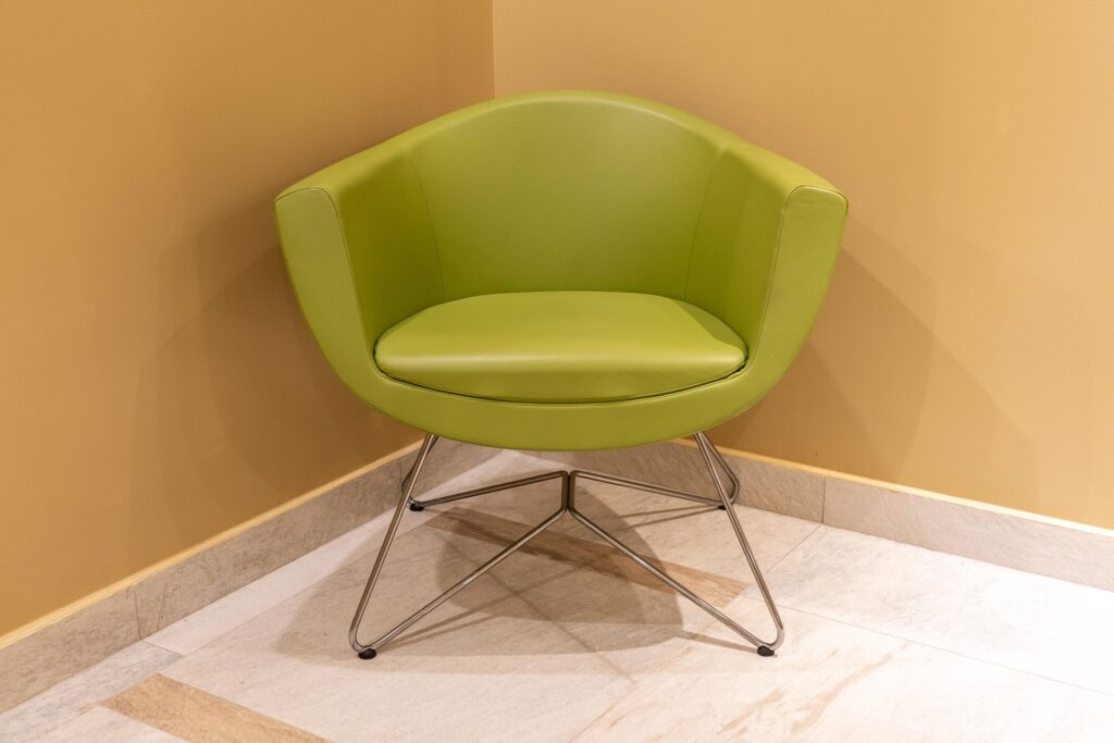 Chartreuse mid-century accent chair with metal legs against warm ochre wall backdrop