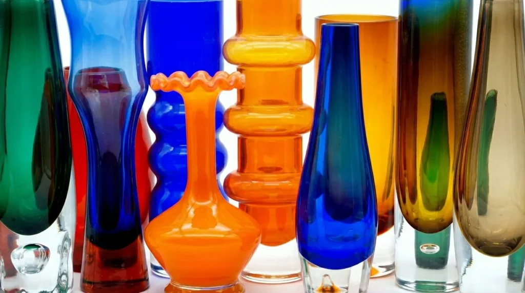 Array of hand-blown glass vessels in jewel tones displaying Nordic design heritage and artisanal craftsmanship